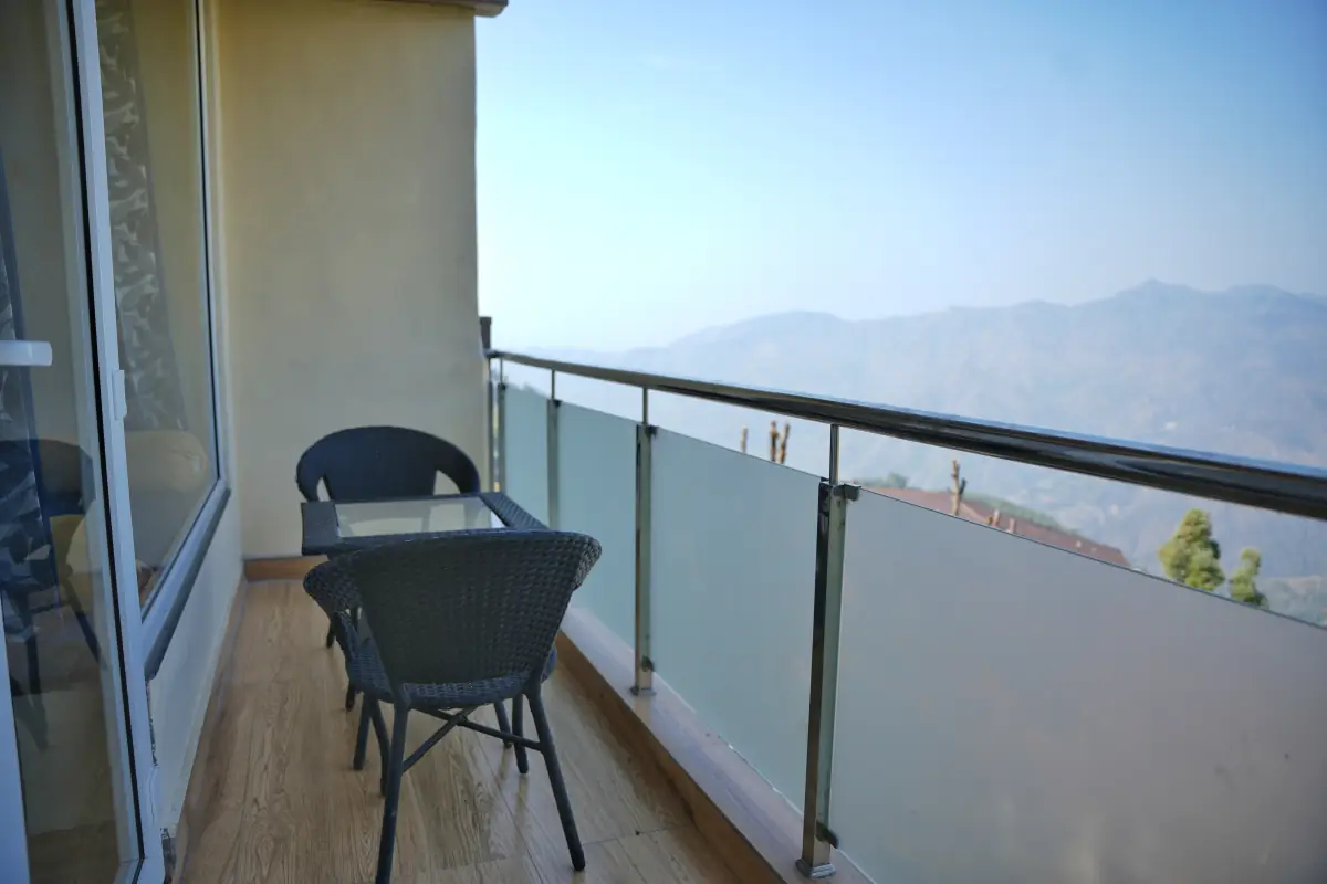 A private balcony with cane chairs and a table, looking out over hazy blue ridges.
